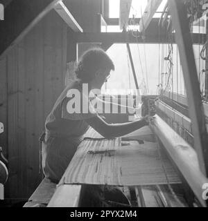 Une femme travaille sur un métier à tisser à l'intérieur de l'usine de tissage. Banque D'Images