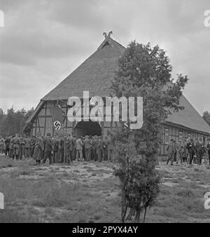 Photo de la façade du Musée de l'agriculture à l'occasion de l'inauguration de la Landtagsplatz à Hoesseringen à Sudebourg dans la Heath de Lueneburg sur 28 juin 1936. A l'entrée de la ferme (maison basse allemande avec toit de chaume et ornements de pignon, chevaux), des représentants des agriculteurs locaux (certains en uniformes sa) se sont réunis. Des drapeaux swastika sont suspendus sur la façade. Banque D'Images