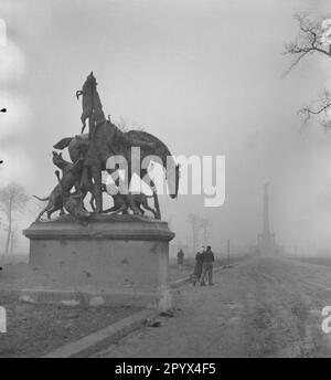 'Photo non datée de la sculpture en bronze néo-baroque partiellement détruite ''Fox Hunt'' des environs de 1900 par Wilhelm Haverkamp (1864-1929) en 1904 à la Fasanerieallee dans le Tiergarten dans l'Ouest de Berlin, qui était une zone d'occupation britannique. En arrière-plan, la colonne de la victoire à la Grande étoile et les passants dans le brouillard. La statue, qui a probablement été décapité par des soldats soviétiques, montre un cavalier de la force de grâce avec une corne de la force de grâce présentant un renard tout en se tenant devant son cheval épuisé. Il est accompagné d'un paquet de huds. Sur la base de la statue, des trous de balle.' Banque D'Images