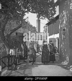 Les femmes portent leurs roues tournantes à travers un village de la côte Baltique à Pomerania (Kamp ou Deep). Banque D'Images