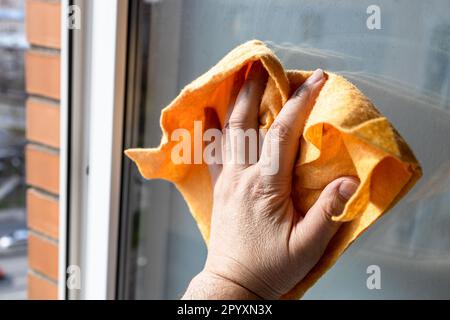 essuie-mains de homme de la surface de verre de fenêtre avec un chiffon dans la maison de ville haute-hauteur le jour ensoleillé de gros plan Banque D'Images