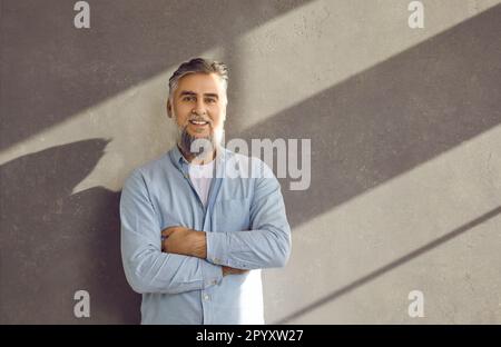 Portrait d'un homme d'affaires mûr et confiant sur fond de mur gris. Banque D'Images