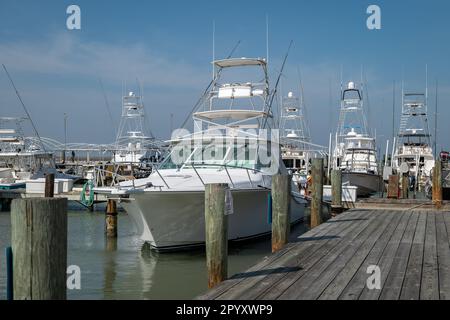 PORT ARANSAS, TX - 22 FÉV 2023: Bateau de pêche sportive ou yacht attaché par corde au pirage de bois au quai dans la marina par une journée ensoleillée. Banque D'Images