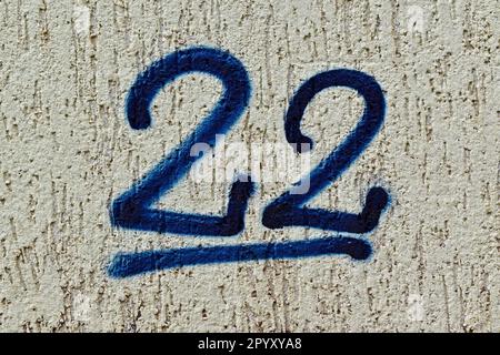 Numéro 22 peint en bleu sur un mur gris Banque D'Images