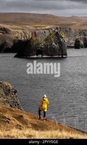 Un jeune homme adulte debout sur un éperon rocheux surplombant un paysage marin pittoresque Banque D'Images