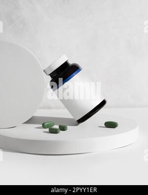 Un pot de vitamine avec des pilules vertes sur fond blanc avec copyspace Banque D'Images