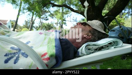 Homme retraité plus âgé dormant sous un arbre pendant la journée d'été. Homme senior qui fait la sieste Banque D'Images