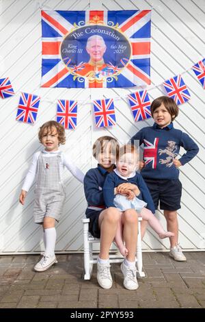 Halesowen, West Midlands, Royaume-Uni. 5th mai 2023. Quatre jeunes frères excités devant la porte de garage de leur famille, décorés prêts pour le couronnement du roi Charles III à Halesowen, West Midlands. Crédit : Peter Lophan/Alay Live News Banque D'Images