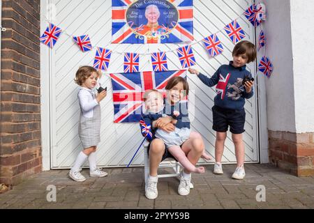 Halesowen, West Midlands, Royaume-Uni. 5th mai 2023. Quatre jeunes frères excités devant la porte de garage de leur famille, décorés prêts pour le couronnement du roi Charles III à Halesowen, West Midlands. Crédit : Peter Lophan/Alay Live News Banque D'Images