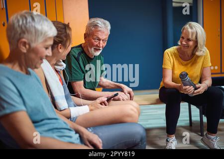 Groupe d'aînés dans le vestiaire après l'entraînement parler et se sentir joyeux. L'homme et les femmes ensemble. Concept de la santé, du mode de vie, de la vie des aînés. Banque D'Images