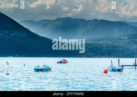 Trois petits voiliers amarrés dans un lac paisible d'Iseo en Italie, avec des montagnes en arrière-plan Banque D'Images