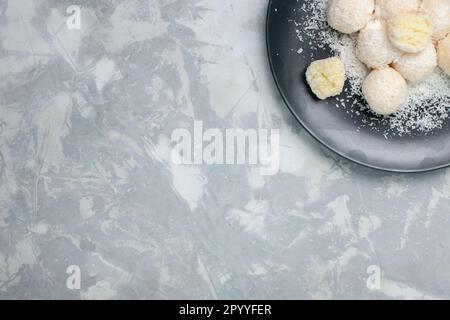 vue de dessus bonbons noix de coco à l'intérieur de l'assiette sur le bureau blanc sucre sucreries doux couleur Banque D'Images