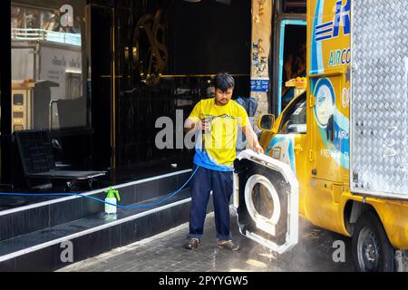 Pattaya,Thaïlande - 17 mars,2023: Rue piétonne Un homme thaïlandais nettoyait le matériel de sa camionnette colorée lors d'une journée chaude et ensoleillée et devant une discothèque. Banque D'Images