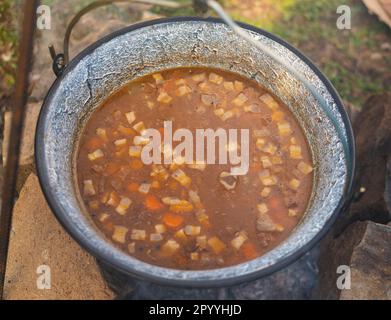 Délicieux repas (goulash) fait de façon traditionnelle dans un pot de poisson sur le feu de camp Banque D'Images