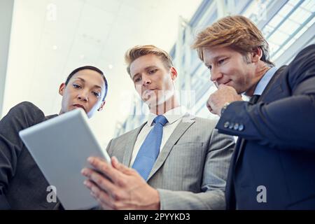Penser à de nouvelles façons de maximiser les profits. un groupe d'hommes et de femmes d'affaires discutant du travail sur une tablette numérique. Banque D'Images