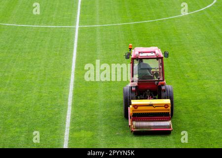 Un homme dans un tracteur équipé d'un semoir à disque a semé de l'herbe sur le terrain de football Banque D'Images