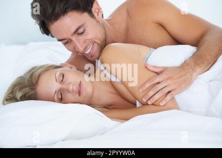 Elle a l'air douce endormi. Un mari embrassant et admirant sa femme alors qu'elle dormait dans le lit à côté de lui. Banque D'Images