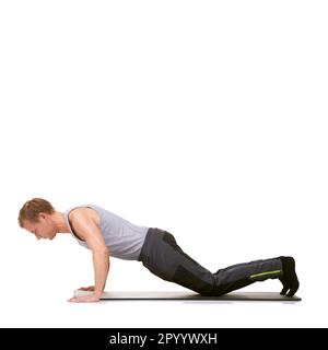 Perfectionner sa technique d'entraînement. Un jeune homme en forme qui s'exerce sur son tapis d'exercice tout en étant isolé sur le blanc. Banque D'Images