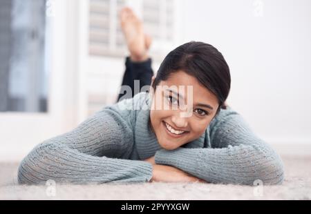 Jamais plus détendu que lorsque vous envoyez des messages instantanés à la maison. Une jolie jeune femme qui se détend sur le plancher de sa chambre. Banque D'Images