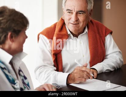 Chercher son fils conseil. Un homme âgé et sa femme remplissent les formulaires à la réception de l'hôtel. Banque D'Images