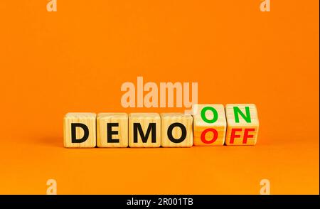 Symbole Démo activé ou désactivé. Homme d'affaires transforme les cubes en bois et le mot Démo désactivé en Démo activée. Belle table orange fond orange. Affaires et dem Banque D'Images