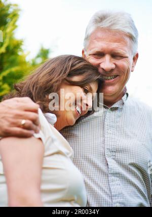 Il me fait toujours rire. un couple senior affectueux qui s'embrasse en plein air. Banque D'Images