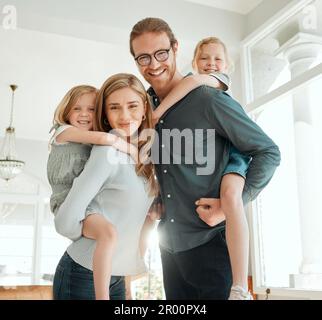 Eh bien toujours avoir maman et papa pour nous soutenir. un jeune couple se tenant ensemble et se liant à leurs enfants en leur donnant des promenades en pigeyback à la maison. Banque D'Images