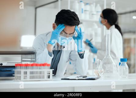 Ne pas obtenir les résultats que j'avais prévus. un jeune scientifique regardant stressé avec un mal de tête. Banque D'Images