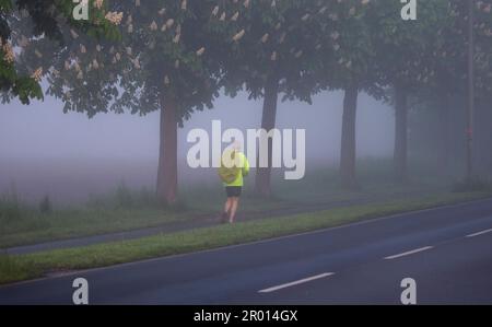 Bornheim, Allemagne. 06th mai 2023. Un jogging court à côté d'une route près de Bornheim dans la brume matinale. Credit: Thomas Banneyer/dpa/Alay Live News Banque D'Images