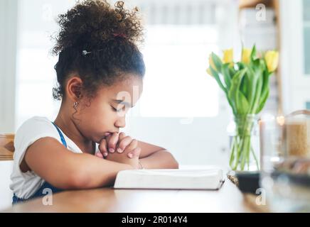 Je suis convaincu que la prière me change. une jeune fille priant à la maison. Banque D'Images