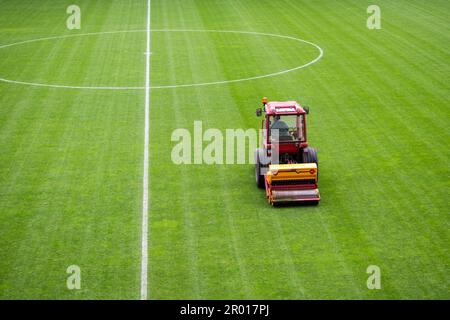 Un homme dans un tracteur équipé d'un semoir à disque a semé de l'herbe sur le terrain de football Banque D'Images