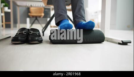 Homme utilisant un repose-pied pour réduire la tension du dos et la fatigue des pieds Banque D'Images