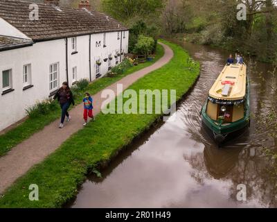 Un helmsman et un fils à la crème et à la barque verte le long de l'avant d'une rangée de cottages blanchis à la chaux sur le Monbucshire et le canal Brecon Talybon-on-Usk Banque D'Images