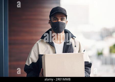 Étaient toujours en train de livrer, juste plus sûr qu'auparavant. un jeune homme masqué livrant un paquet à un lieu de résidence. Banque D'Images