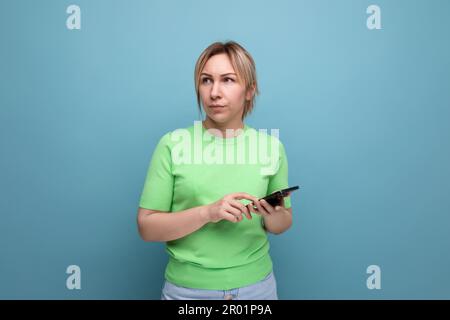 indignant belle blonde fille avec des gadgets dans sa main sur un fond bleu avec espace de copie Banque D'Images