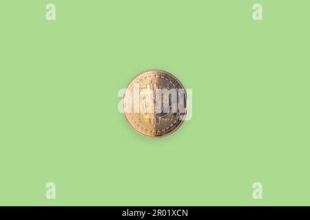 Pièce en bitcoin dorée isolée sur fond vert clair Banque D'Images