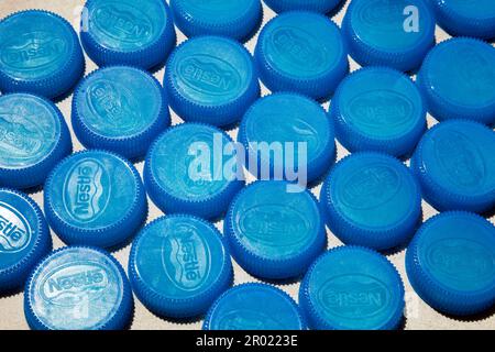 Ho Chi Minh ville, Vietnam - 2 mai 2023: Beaucoup de bouchons de bouteille en plastique bleu avec logo Nestlé disposés en rangées arrière-plan. Nom de la société sur un groupe de drinki Banque D'Images