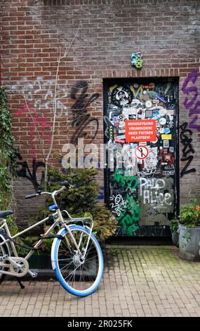 Scène typique de rue d'Amsterdam avec des graffitis d'art de rue et des vélos garés. Banque D'Images