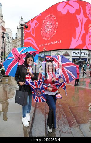 Londres, Royaume-Uni. 6th mai 2023. Les supporters portant des vêtements rouges, blancs et bleus avec des parasols Union Jack regardant le message de Coronation pour le couronnement du roi Charles III, à Piccadilly Circus, Londres dire heureux et glorieux et Dieu sauver le roi crédit: Paul Brown/Alay Live News Banque D'Images