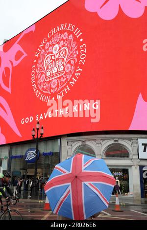 Londres, Royaume-Uni. 6th mai 2023. Les supporters portant des vêtements rouges, blancs et bleus avec des parasols Union Jack regardant le message de Coronation pour le couronnement du roi Charles III, à Piccadilly Circus, Londres dire heureux et glorieux et Dieu sauver le roi crédit: Paul Brown/Alay Live News Banque D'Images