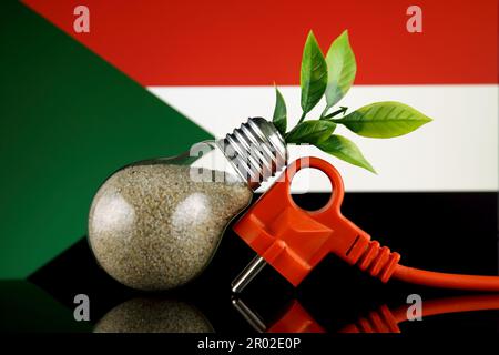 Bouchon, plante poussant à l'intérieur de l'ampoule et drapeau du Soudan. Concept d'énergie renouvelable écologique. Banque D'Images
