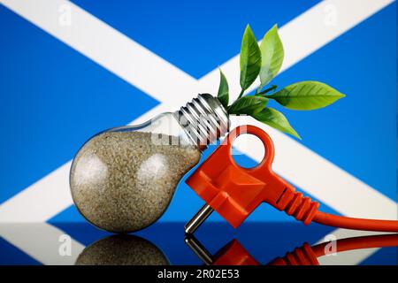 Bouchon, plante poussant à l'intérieur de l'ampoule et drapeau écossais. Concept d'énergie renouvelable écologique. Banque D'Images