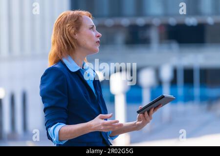 Professionnel d'entreprise féminin innovant et expert en technologie Red-Hest collaborateur avec ses collègues via une tablette numérique au cours d'une entreprise à distance Banque D'Images