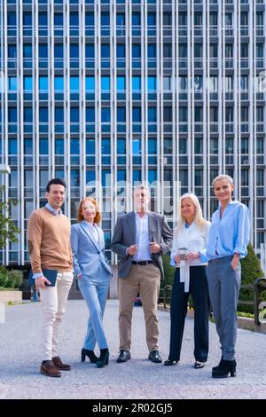 Portrait d'un groupe joyeux de collègues marchant à l'extérieur dans un bureau d'entreprise en riant Banque D'Images