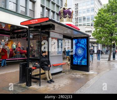 Londres, Royaume-Uni. 6 mai 2023. Une grande couronne orne le toit d'un abri d'autobus près du magasin phare John Lewis sur Oxford Street le jour du couronnement du roi Charles III et de la reine Camilla, tandis qu'un message numérique est affiché sur un écran à l'abri d'autobus. Il s’agit du premier couronnement du Royaume-Uni depuis 70 ans et du premier à avoir lieu à l’ère numérique. Credit: Stephen Chung / Alamy Live News Banque D'Images