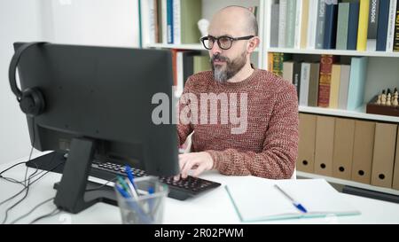 Jeune homme bald étudiant utilisant l'ordinateur étudiant dans la classe d'université Banque D'Images
