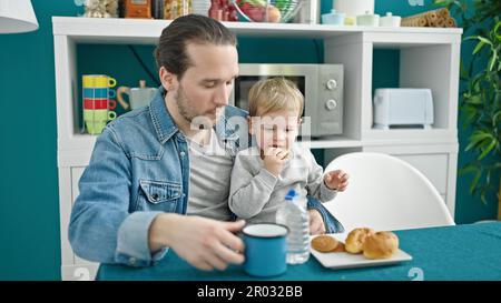 Le père et le fils sont assis sur une table pour prendre le petit déjeuner dans la salle à manger Banque D'Images