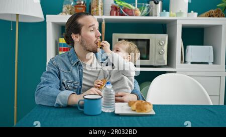 Le père et le fils sont assis sur une table pour prendre le petit déjeuner dans la salle à manger Banque D'Images