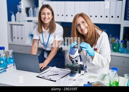 Mère et fille scientifiques utilisant un ordinateur portable et un microscope au laboratoire Banque D'Images