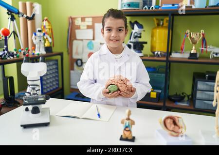 Adorable fille hispanique étudiant scientifique tenant le cerveau dans la salle de classe de laboratoire Banque D'Images